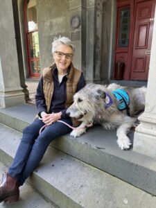 Amanda sitting on the steps outside Alia College, with her friendly dog beside her.